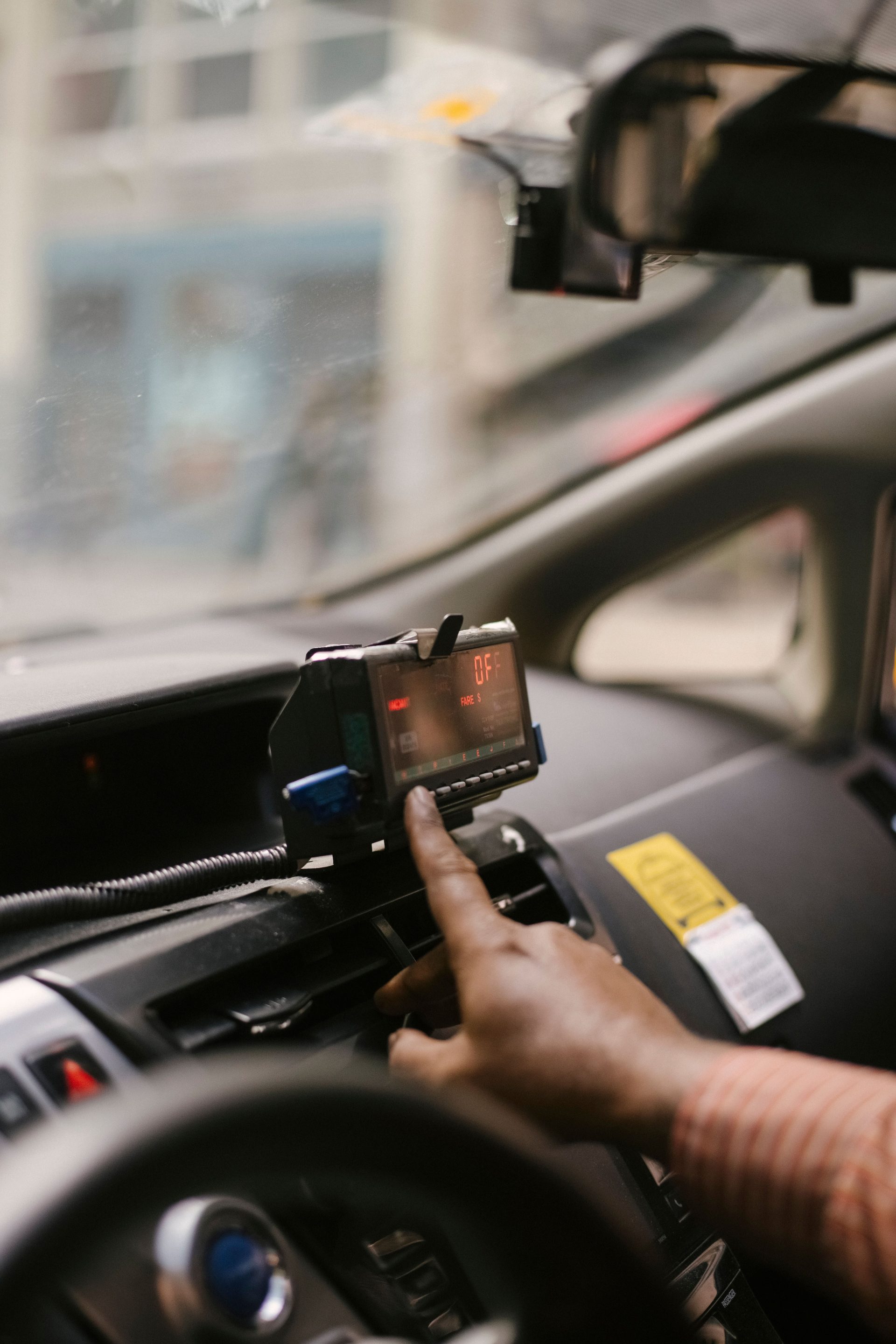 Unrecognizable ethnic male driver sitting in cab with blurred background and using navigator to find way to drive during ride